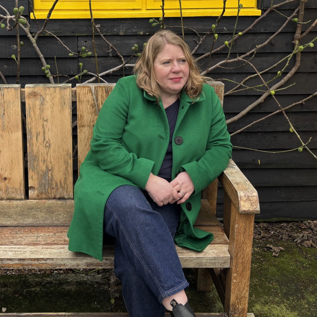 A portrait of journalist Emily Brooks, sitting on a bench